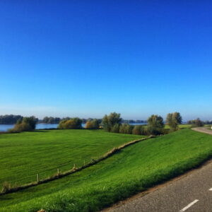 Rivierlandschap met groene weilanden en kronkelende weg