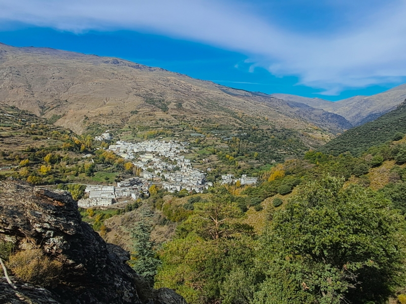 Bergdorp omringd door herfstbomen onder blauwe lucht