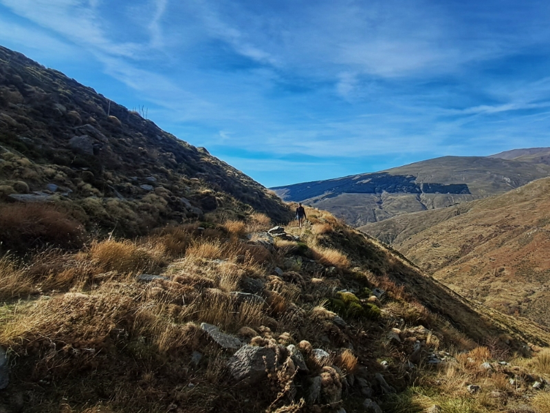 Wandelaar op bergpad met blauwe hemel