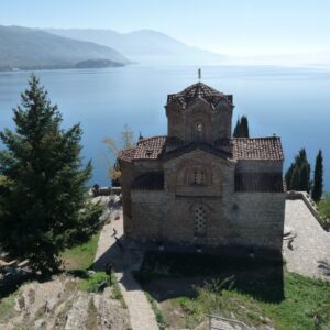 Oude kerk met uitzicht op meer en bergen.