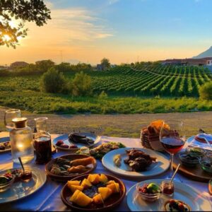 Eten bij zonsondergang met wijngaarden en bergen op achtergrond.