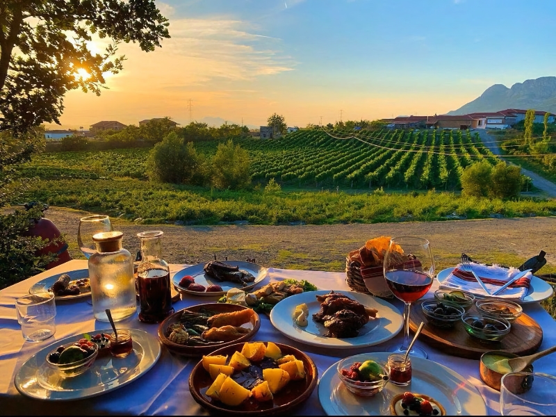Eten bij zonsondergang met wijngaarden en bergen op achtergrond.