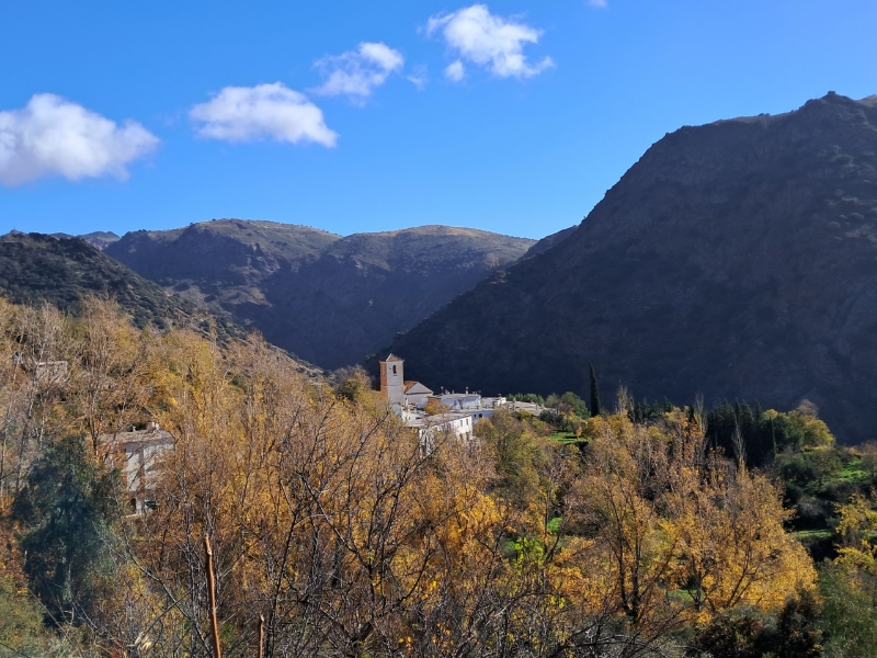 Bergdorp in vallei omgeven door herfstlandschap.