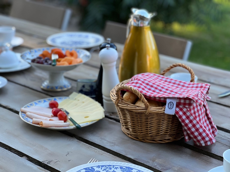 Ontbijttafel met brood, kaas en fruit buiten.