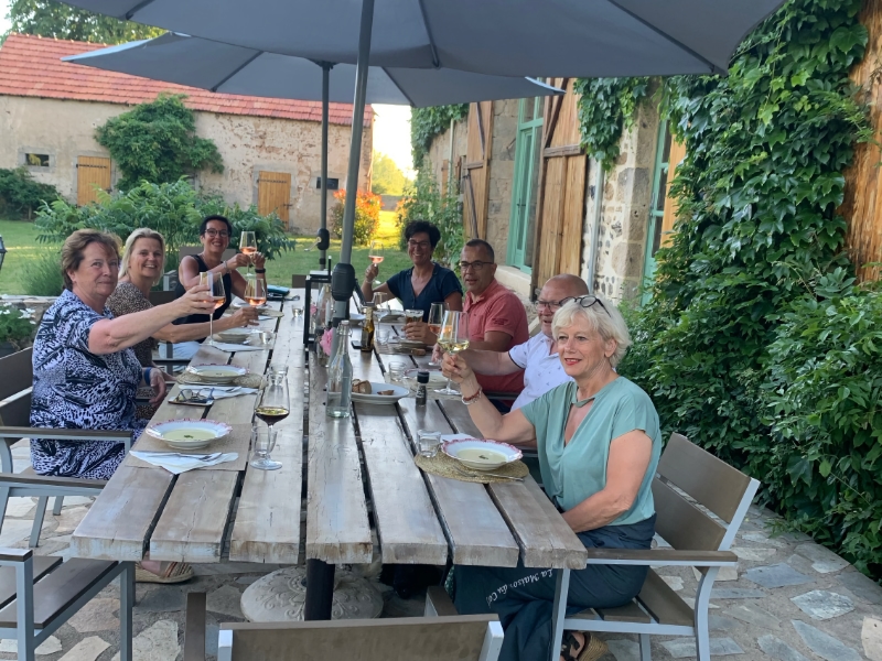 Groep mensen dineert buiten aan lange tafel.