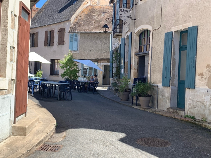 Rustig straatje met buitenterras en oude gebouwen.