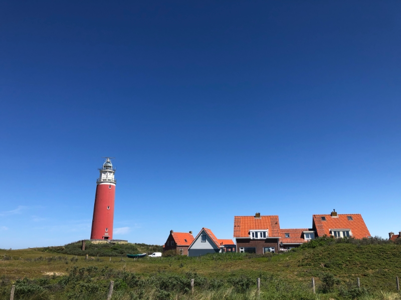 Vuurtoren naast huizen onder blauwe lucht