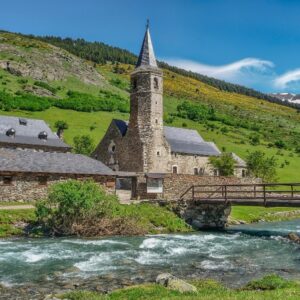 Middeleeuwse kerk in groene vallei met brug en rivier.