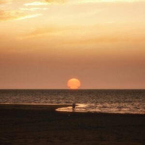 Romantische zonsondergang aan zee met wandelend koppel.
