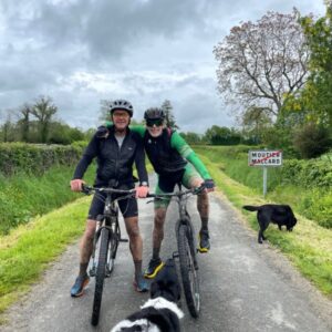 Twee fietsers met honden op landweg bij Moultier.