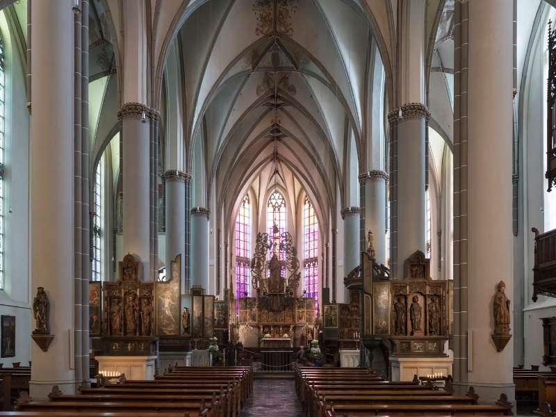 Interieur van een gotische kerk met gebrandschilderde ramen.