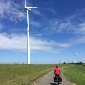 Fietser op weg langs windturbines in het landschap.