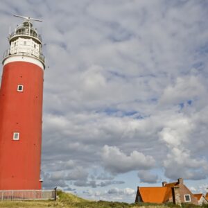 Rode vuurtoren naast huisjes met oranje daken