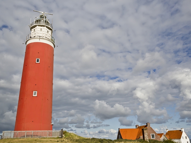 Rode vuurtoren naast huisjes met oranje daken