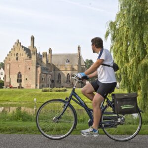 Fietser kijkt naar historisch gebouw bij water