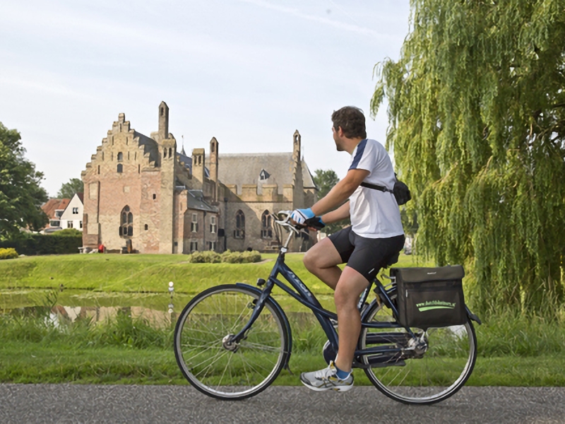 Fietser kijkt naar historisch gebouw bij water
