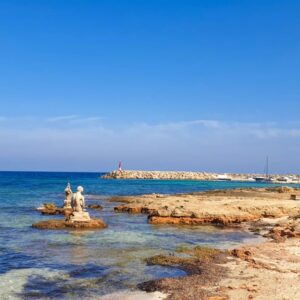 Kust met beelden en vuurtoren bij blauwe zee