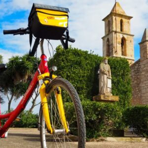 Fiets bij kerk en standbeeld op zonnige dag
