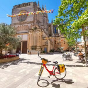 Rode fiets voor zonovergoten kerkplein met versieringen