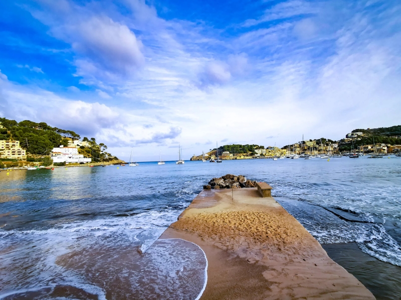 Strandpad naar zee met boten en heuvels