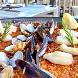 Paella met zeevruchten en citroen op tafel.