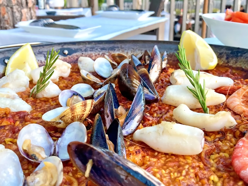 Paella met zeevruchten en citroen op tafel.