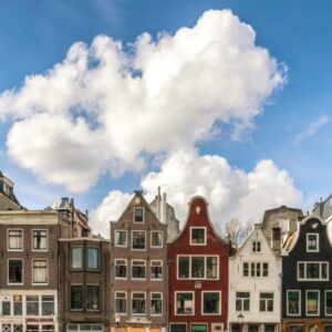 Rij traditionele Nederlandse grachtenpanden bij zonnige hemel.