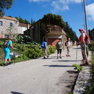 Groep wandelaars in zonnig dorp met rugzakken