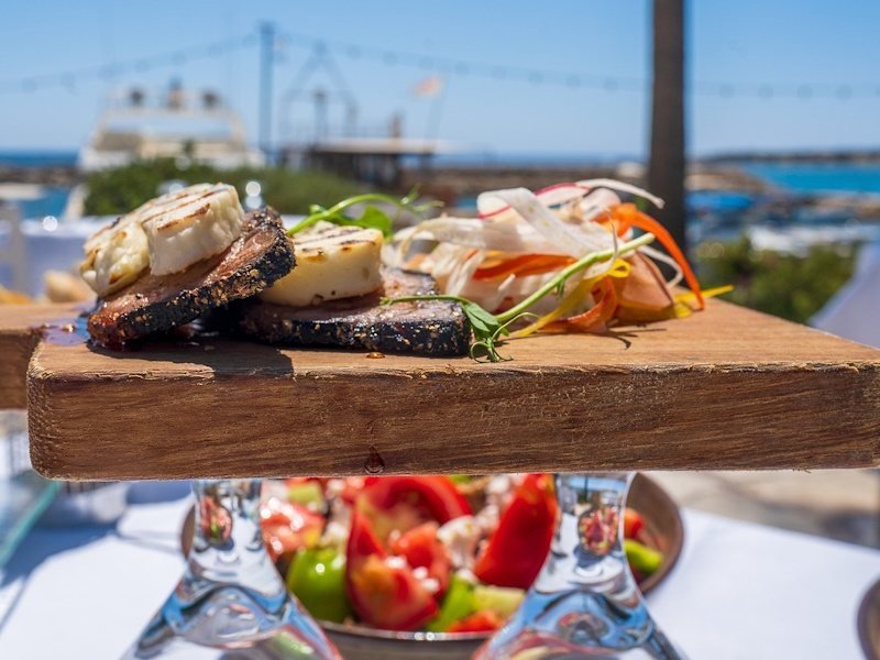 Gourmet gerecht op houten plank bij zeezicht.