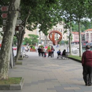 Mensen wandelen op trottoir naast rivier en gebouwen