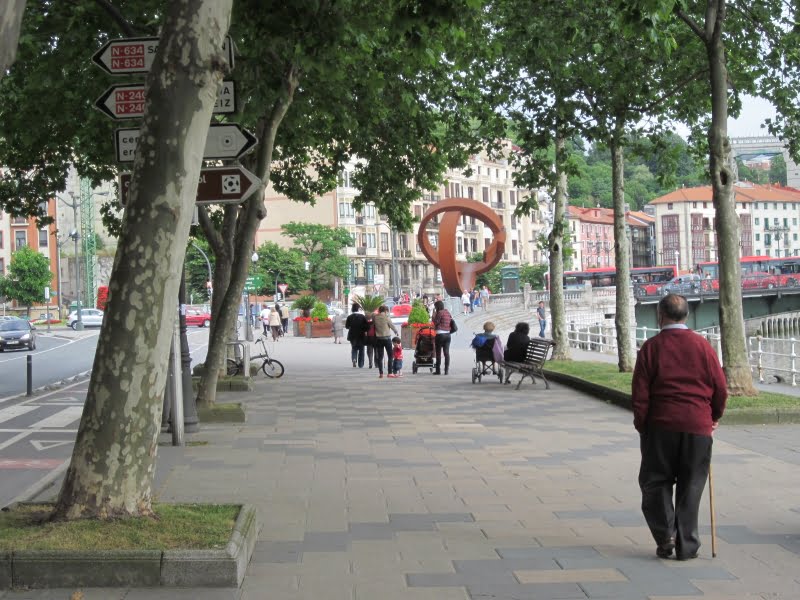 Mensen wandelen op trottoir naast rivier en gebouwen