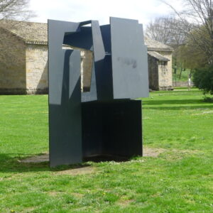 Abstract beeldhouwwerk op grasveld bij stenen gebouw.