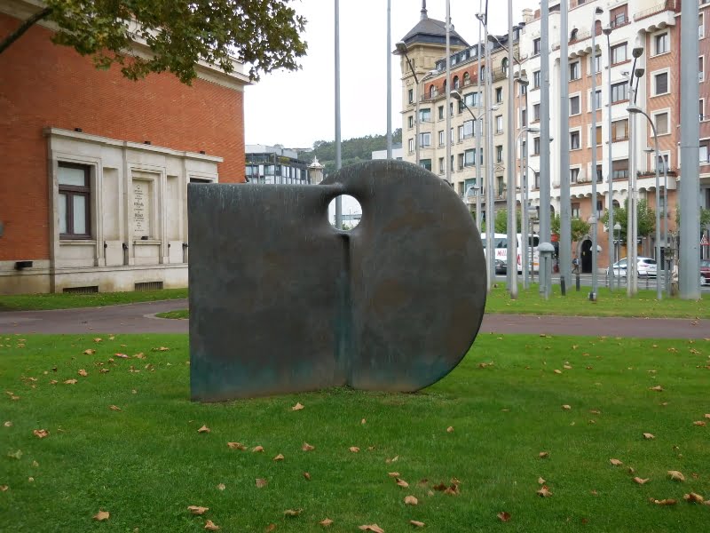Abstract beeldhouwwerk in stedelijke omgeving met grasveld