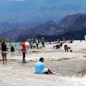 Mensen genieten van warmwaterbronnen met berglandschap op achtergrond.