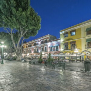 Avondzicht op verlichte stadspromenade met bomen en gebouwen.