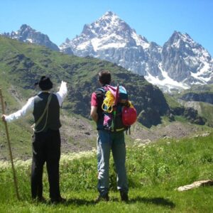 Twee wandelaars wijzen naar besneeuwde bergen.