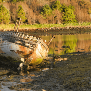 Verlaten schip op oever in zonsondergang
