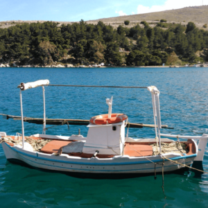 Kleine vissersboot drijft op blauw water, groene heuvels.