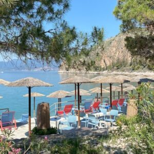 Strandstoelen onder parasols bij zee en bergen.