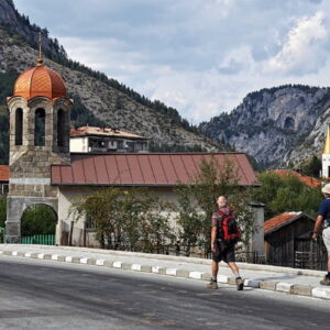 Wandelaars passeren kerk in bergachtig dorp