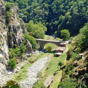 Oude stenen brug in groene vallei met rivier.