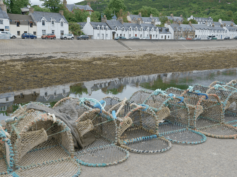 Vissersnetten op de kade, huizen op achtergrond.