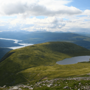 Uitzicht op bergen en meer onder bewolkte hemel.