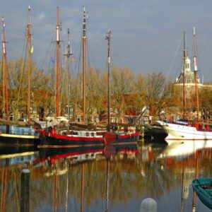 Historische haven met boten en kerk op achtergrond.