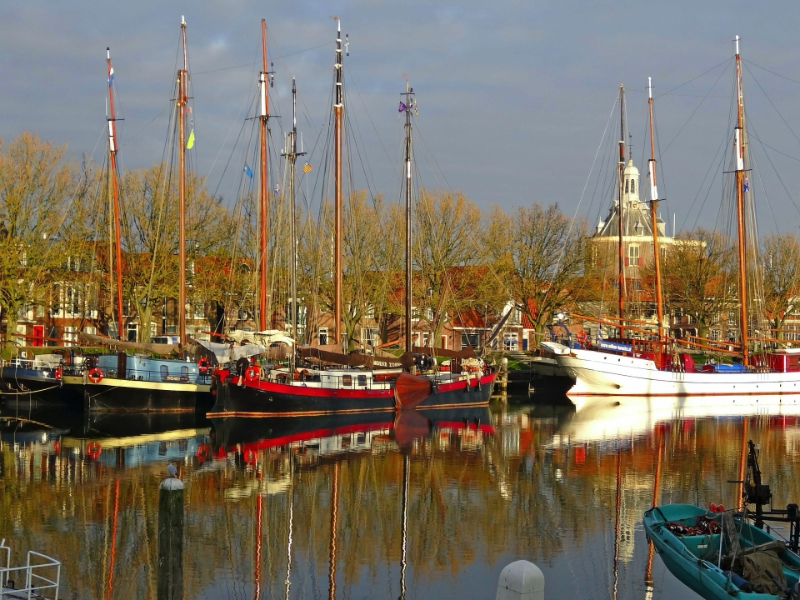 Historische haven met boten en kerk op achtergrond.