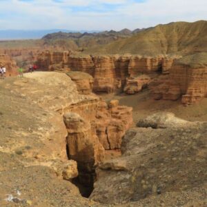 Wandelaars bij rotsachtige canyon met blauwe lucht.