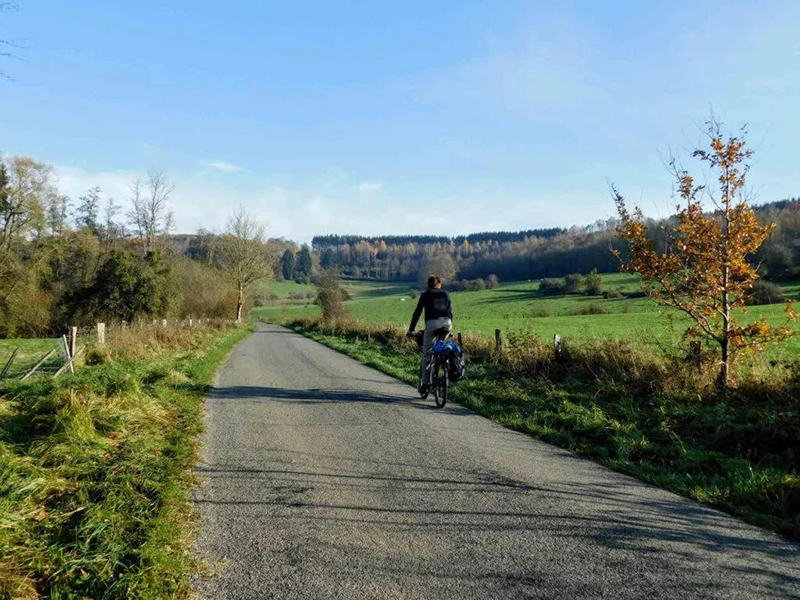 Fietser op rustige landweg in herfstlandschap.