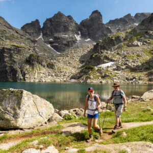 Twee wandelaars bij bergmeer en rotsachtige bergen