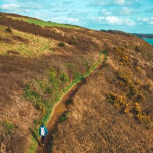 Wandelaar op een pad tussen groene heuvels.