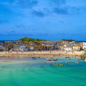 Strand met boten en dorp aan zee in Engeland.